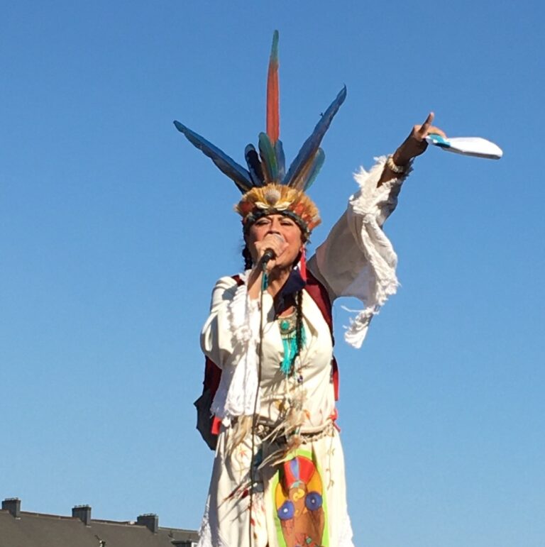 On Saturday, October 10th, Chali'Naru Dones of the United Confederation of Taino People, stands atop the plinth where the decapitated statue of Christopher Columbus once stood, on the Boston waterfront. The crowd responded, "City by city, town by town, Christopher Columbus must come down!" photo: Claire Gosselin / Mass Peace Action